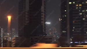 View from the side of city skyline buildings. Driving along Dubai skyscraper building. Tracking shot from the side of modern skyscraper buildings in Dubai UAE at night
