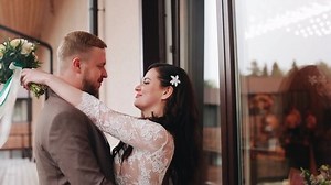 Two lovers kiss near a large window standing in the wind. In the hands of the girl a bouquet of flowers.