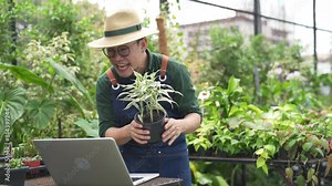 Happy Asian man plant shop owner using laptop computer live streaming broadcasting presentation potted plants and flowers selling to customer. Modern small business online shopping e-commerce concept.