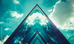 Reflection transforms the skyline as a striking glass pyramid ascends against a vibrant blue sky, merging architecture with natures beauty.