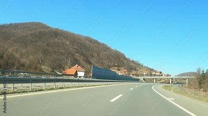 Driving down the highway through Serbia in winter, with snow melting on surrounding hills, dashcam pov driving plate footage in real time