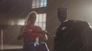 Fitness young woman using rowing machine in the gym crossfit training. Slow-motion shot