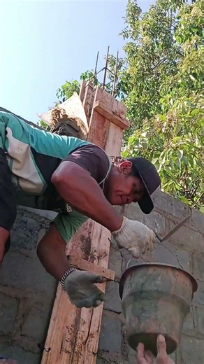 filling the cast mixture in the concrete brick wall column using a small bucket.