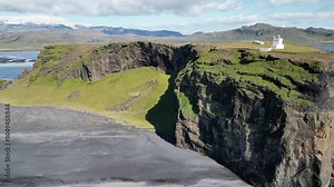 Aerial view of a lighthouse on a rock on the ocean shore in Iceland. Arctic nature landscape rocky ocean shore with black sand beach, tourism and travel. High quality 4k footage