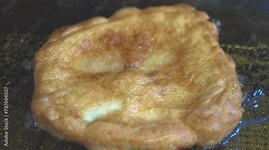 Process of making deep-fried italian donuts and pancake. Professional kitchen equipment. Deep fry italian donut dough using professional fryer. Slow motion close up oil boiling preparing big donuts