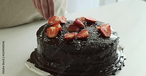 Man skillfully decorates a chocolate cake. With a steady hand and a creative vision, he adds intricate designs and embellishments to elevate the cake to a work of edible art.