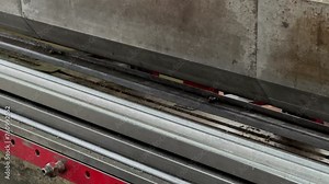 Close up shot of operator using bending machine to make indentations in iron plate sheets. Hand wearing cloth glove holding iron plate on bending machine