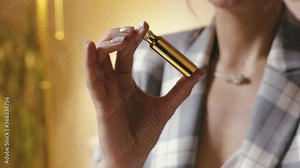 Close-up of a woman's hands mixing perfume ingredients in a Golden test tube. The perfumer prepares Cologne in the workshop, shakes essential oils in a container. The concept of a micro business