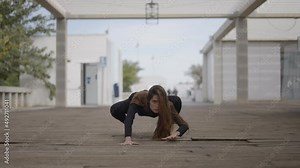Young woman outdoors moves on all fours like a cat, static ground view