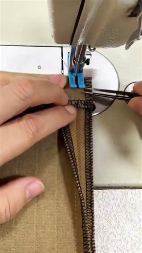 sewing a dark brown fabric with a black border using a professional sewing machine in a workshop