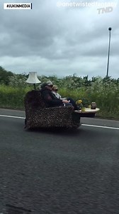 Couple driving down the road on a couch on wheels