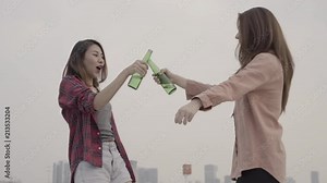 Slow motion - Group young asian women people dancing and raising their arms up in air to music played by dj at sunset urban party on rooftop. Young asian girls friends hanging out with drinks beer.