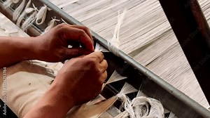 Silk weaving machine in operation. The girl works at the machine creating. Woman weaving on a traditional loom. Hand weaving cotton. Traditional cotton weaving.