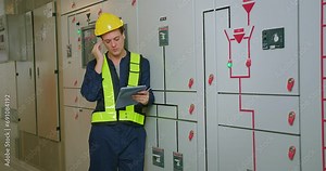 electricians electrical engineer in protective uniform wearing hard hat checking voltage control panel system at electrical cabinet for generate electricity of factory in manufacture industrial