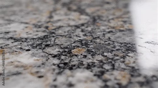 Close up view of polished granite countertop with reflections of light and patterns of specks