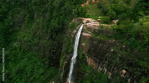 Diyaluma Falls cascade down Sri Lanka mountains, rich green plants surrounds the waterfall. Aerial drone footage captures the natural wonder, tranquil waters flow from a height in landscape.