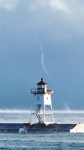 A large steam spout dances over Lake Superior behind the Grand Marais, MN breakwall lighthouse | Nathan Klok Photography