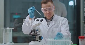 COVID-19 testing in laboratory, male technician is doing PCR and serology tests, using tubes with samples and microscope