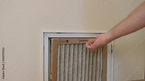 HVAC service technician replacing dirty indoor air filter in residential heating and air conditioning system. Home air duct ventilation system maintenance for clean air.