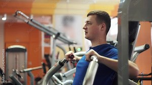 Male training chest muscles using exercise machine for body mass. Weight pushing