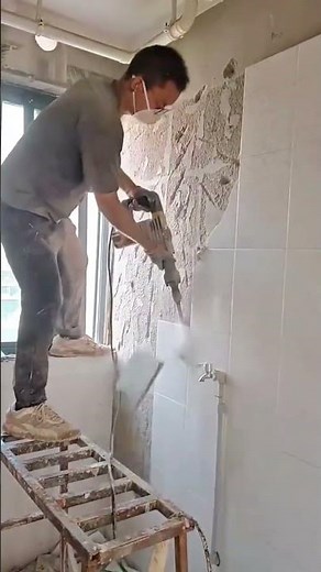 Removing old wall tiles with a power tool to prepare the surface for renovation