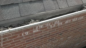 Dirty, metal gutters on a residential home are clogged with leaves and debris.