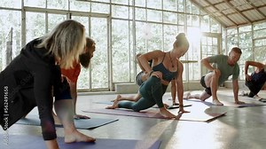 Female yoga instructor leading students through their movements during a class in her studio