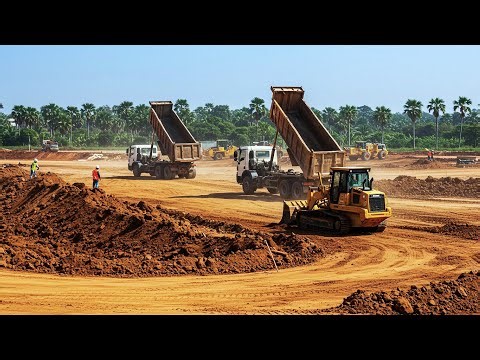 A large scale earthmoving construction site with dump trucks and bulldozers pushing the mud soil