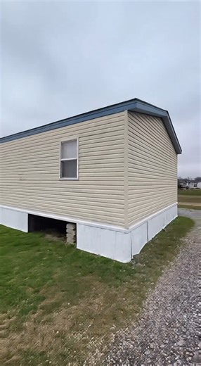 used manufactured home listed at $15,250. From the outside, the home looks simple but stable, sitting level with straight windows and a clean roofline. Inside, the flooring feels firm and the living area opens up more than expected. The kitchen appears early in the layout with worn but functional cabinets and working plumbing. The bedroom sits closer to the center, offering clean walls and solid flooring. The bathroom is fully usable, though the shower head will need replacement. This home isn’t