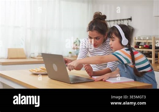 Woman helping girl using laptop together Stock Video Footage - Alamy