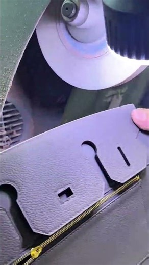 Polishing the edges of a high quality leather bag using a professional grinding machine in a factory