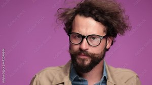 cool bearded young man with long beard and moustache fixing jacket, taking glasses off and making a scene, having an episode, putting glasses on and recovering on pink background in studio