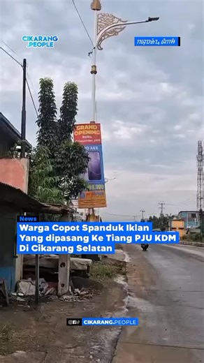 • Warga melepas Spanduk Iklan Salah Satu Toko Electronic yang diduga dipasang tanpa izin di tiang Penerangan Jalan Umum (PJU) milik Pemerintah di pinggir jalan Raya KH R Ma'Mun Nawawi Cibarusah, Kampung Kandangroda, Kecamatan Cikarang Selatan, Kabupaten Bekasi (29/12/25) Warga Menilai PJU Baru Dipasang Berornamen Khas Sunda Yang di Gagas oleh Gubernur Jabar Menjadi Tak indah dan tidak sesuai peruntukan. Tiang PJU pemerintah digunakan untuk penerangan jalan, bukan sebagai media pemasangan iklan A