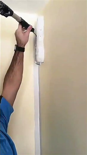painting white walls in a room using a long handled paint roller very smoothly