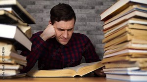 Man student boring reading book at library with a lot of books in university.