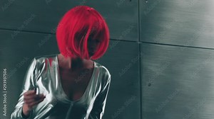 Girl in a futuristic style. she is wearing an orange wig and a silvery tight-fitting suit. girl from the future. The actress plays the role of a creature from another planet.