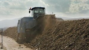 Industrial compost production site. Slow motion footage of large compost turning machine mixing compost piles