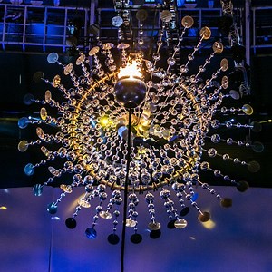 For the 2016 Olympic opening ceremony in Rio, American kinetic artist Anthony Howe designed and built a large sculpture that amplified and reflected light from the fire within the cauldron. The metal art installation was made up of hundreds of reflective spheres and plates organised concentrically around the cauldron and supported by a metal ring. Each piece was designed to rotate independently around the ring, creating a pulsating movement and millions of reflections from the cauldron's flame. 
