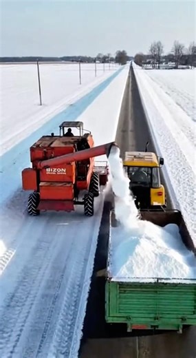Wait, is he currently cutting snow with a combine and loading it onto a trailer?