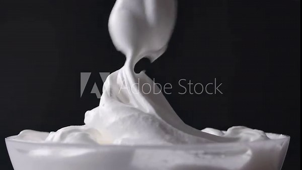Chef mixes whipped egg whites with sugar and stirs with a spoon, dessert preparation process, close-up of food