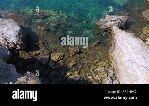 Aerial drone view of rocky coastline with cove and peninsula along a dramatic empty shore. Birds eye footage reveals rugged relief, steep seaside landforms, isolated blue water, remote scenery. rocky, coast, cove, aerial, drone, sea, peninsula Stock Video Footage - Alamy