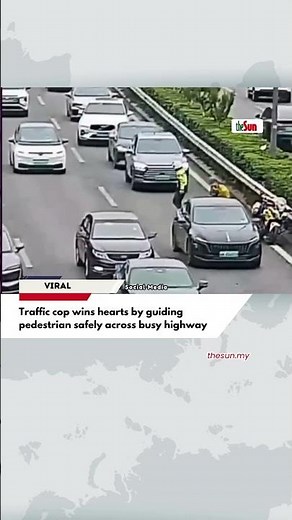 Traffic cop wins hearts by guiding pedestrian safely across busy highway