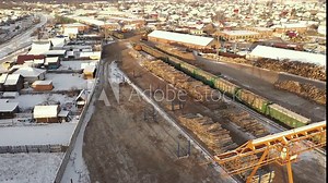 Freight train near a woodworking factory, woodworking factory aerial view. A logging train at sawmill with stacked wooden logs and tree trunks. Modern woodworking factory with a railway junction