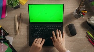 Anonymous Designer Typing on a Laptop with Mock Up Green Screen Chromakey Display with Motion Tracker Placeholders.Illustrator Using a Computer, Working on a Digital Art Portfolio. Top Down View