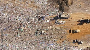 Aerial footage of a Municipal Solid waste Landfill during collecting, sorting and pressing work, with a massive flock of birds.