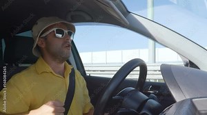 Man driving car, dancing and listening to music. Man singing and dancing happy driving car in city. Crazy men driving a car. Guy in a hat and sunglasses.Slow motion.