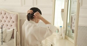 A captivating woman stands before a mirror, gazing at own reflection with a mix of confidence and admiration. Her alluring presence demeanor are captivating as she delicately adjusts her hairstyle.