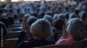 Grateful audience applauding. View from the back of auditorium or theatre with people seated in an concert watching a live performance on a stage