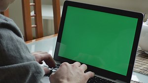 Man typing on a macbook with a green screen - Free Stock Video