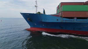 Side View of a Large Blue Cargo Ship Loaded with Shipping Containers Sailing Through Calm Waters
